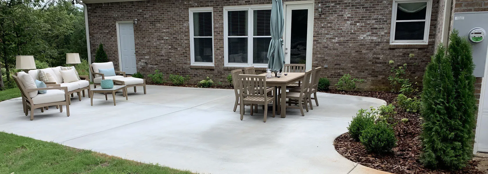 Broom-finish concrete patio with outdoor furniture behind a brick home near Madison, AL