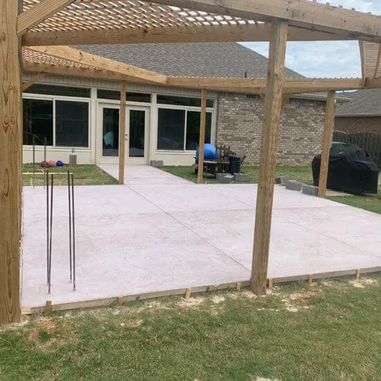 Concrete slab poured beneath a wood pergola frame at a North Alabama home