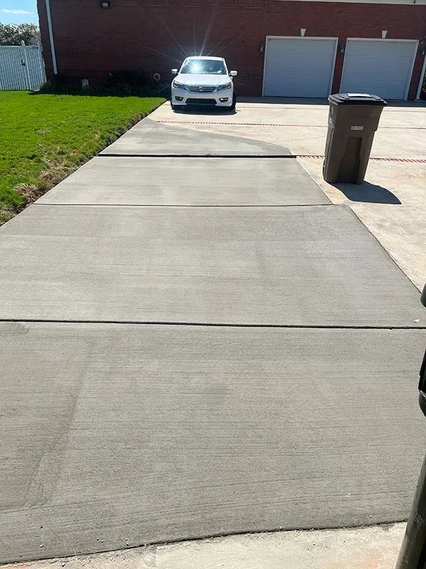 Wide concrete driveway leading to a two-car garage at an Alabama home