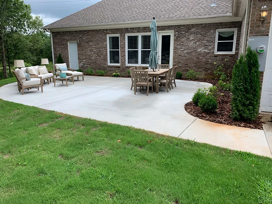 Finished concrete patio with landscaping behind a brick home, poured by Battle Concrete